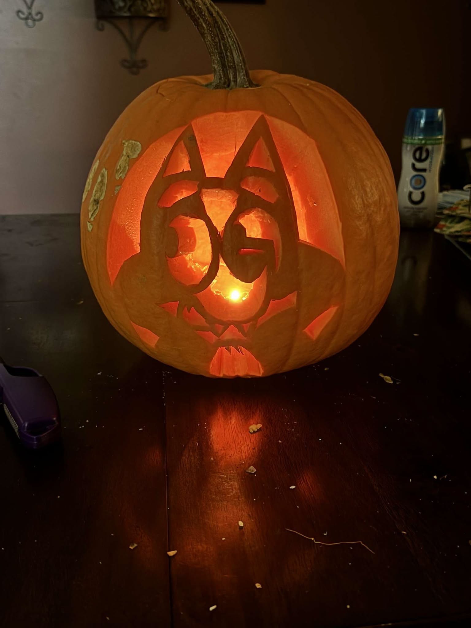 A lit carved jack-o-lantern glowing on a dark table